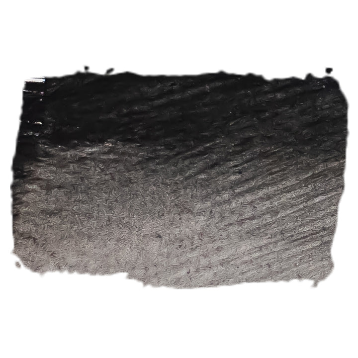 Brushed swatch of Chroma Atelier Carbon Black acrylic ink on white, showing a dense black that thins to grey where the brush runs dry