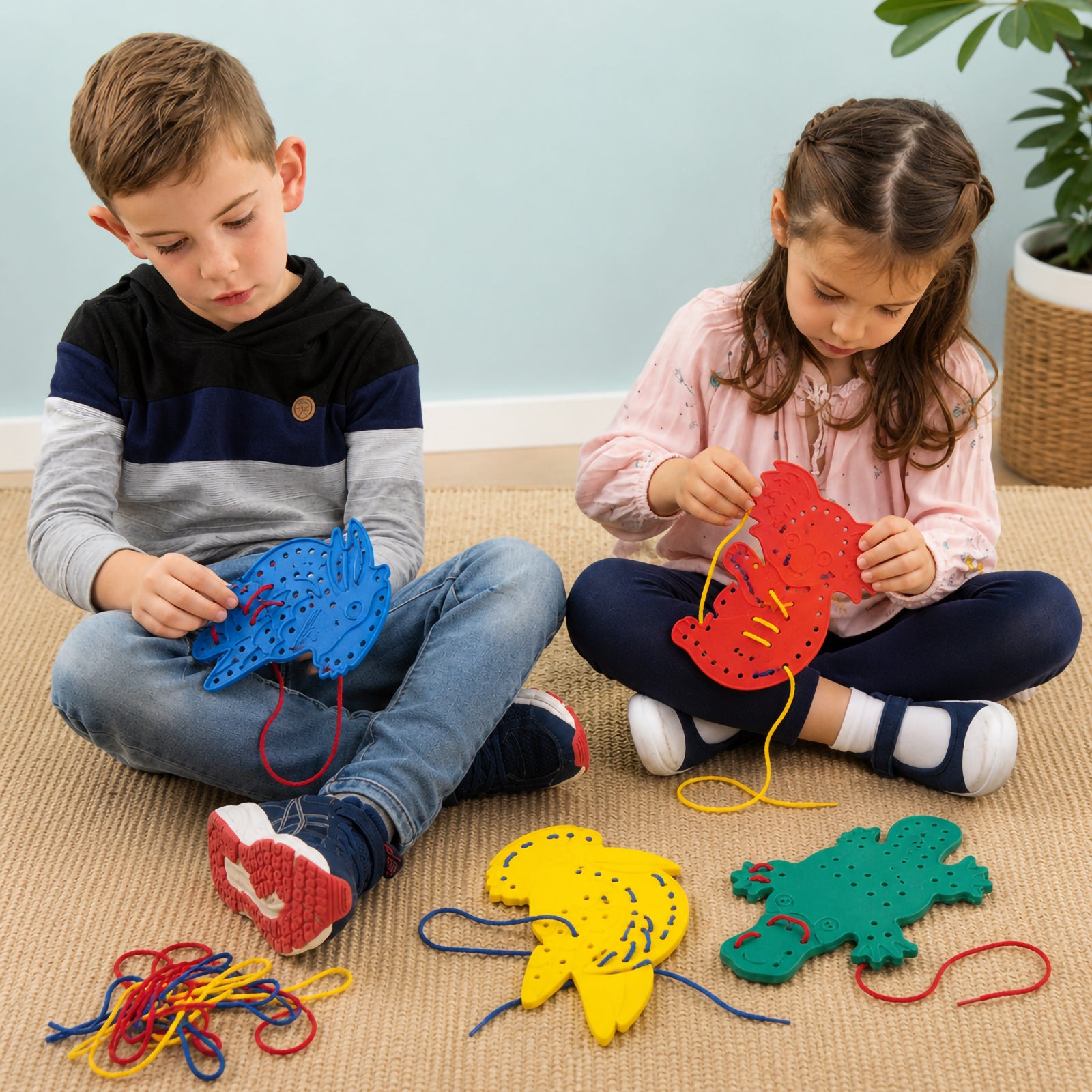 Two children sitting on a classroom rug using colourful Australian animal lacing shapes including a blue platypus and red koala while threading bright laces through the holes.