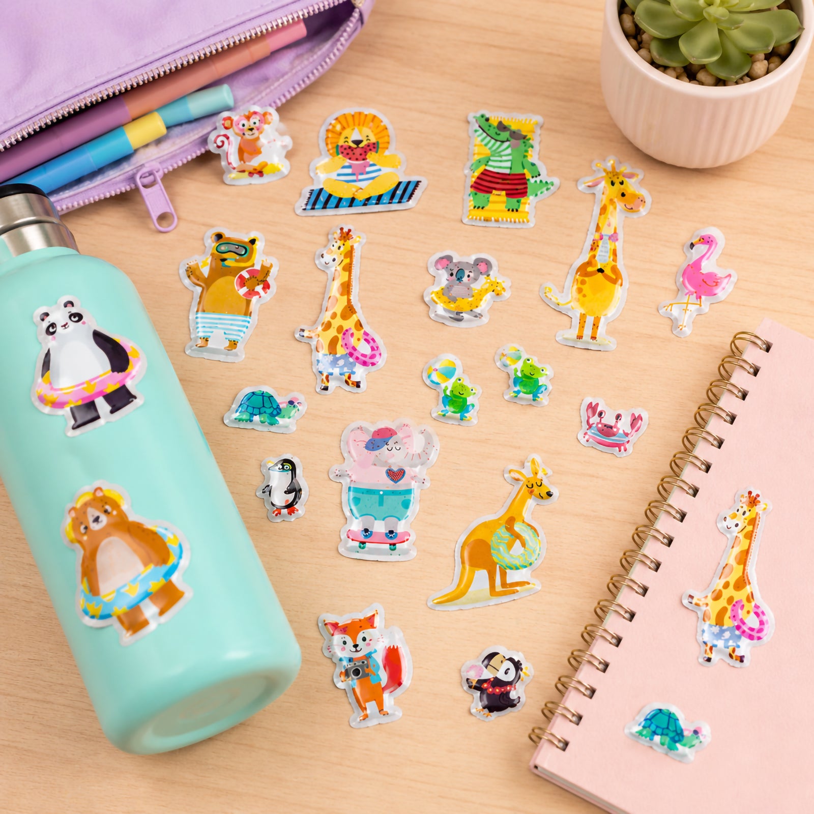 Beach themed puffy stickers arranged across a desktop with notebooks and stationery. The bright collection features tropical animals, sea creatures and holiday inspired characters designed to encourage imaginative play and creative decorating.