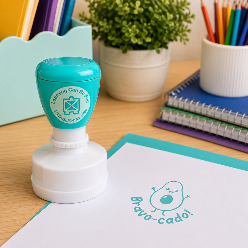 Learning Can Be Fun Bravo-cado reward stamp positioned beside stationery organisers, notebooks and classroom supplies. The bright aqua impression demonstrates how educators can provide positive reinforcement and motivational feedback during everyday learning activities.
