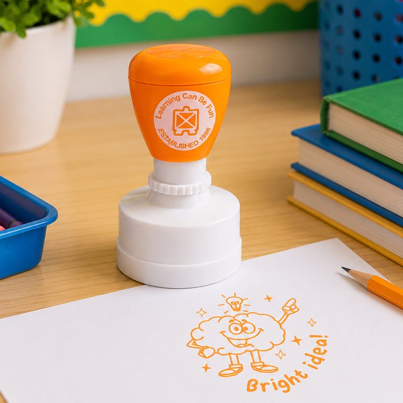 Classroom themed product image showing the self inking merit stamp beside books, pencils and educational supplies. The cheerful brain illustration and motivational message encourage confidence and creative learning.