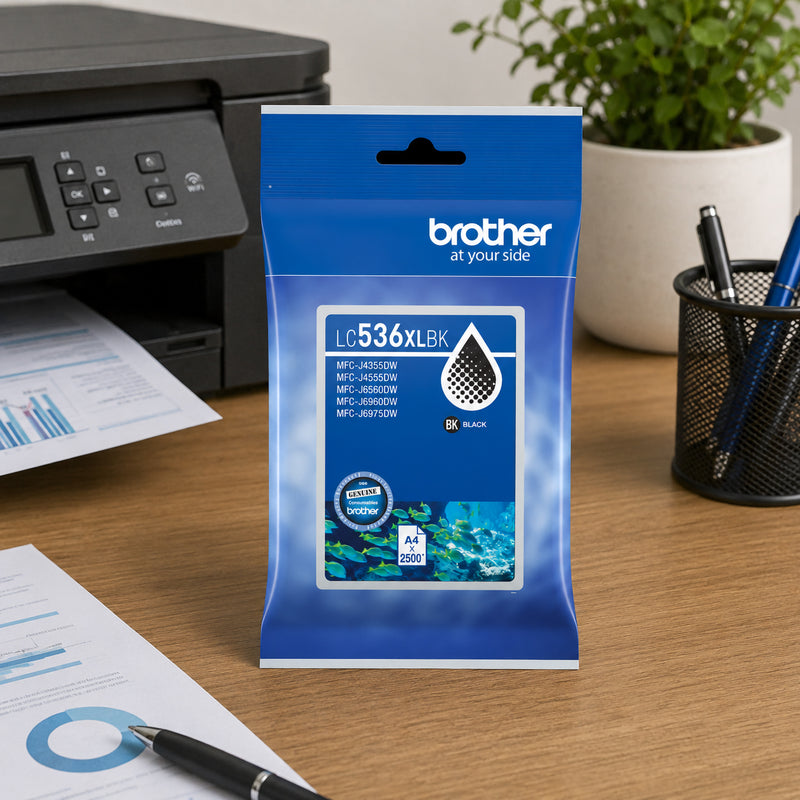 Brother LC536XLBK High Yield Black Ink Cartridge displayed on a clean office desk beside a Brother multifunction printer. The packaging stands upright near a notebook, printed business documents and an indoor plant, creating a productive workspace environment. The image highlights the cartridge as a dependable choice for everyday office printing, professional documents and high volume business tasks.