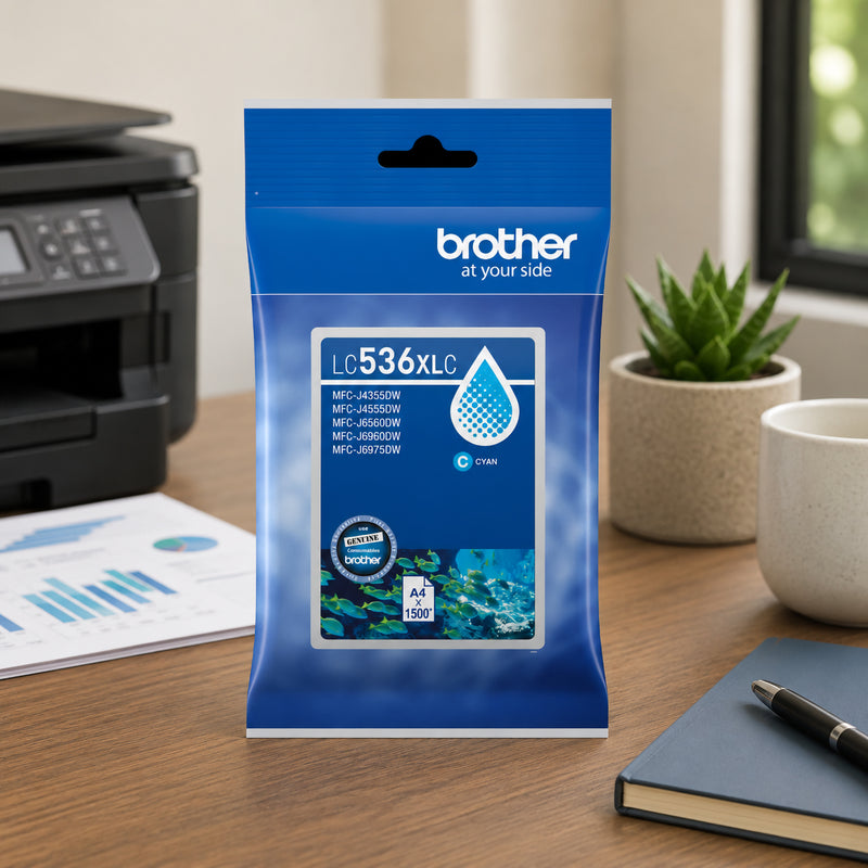 Brother LC536XLC genuine cyan ink cartridge package positioned on a desk next to a Brother printer, printed charts and office accessories. A small potted plant and notebook add a professional workplace atmosphere while the packaging remains the focal point. The scene highlights the cartridge's role in producing clear graphics, colourful reports and consistent colour output.
