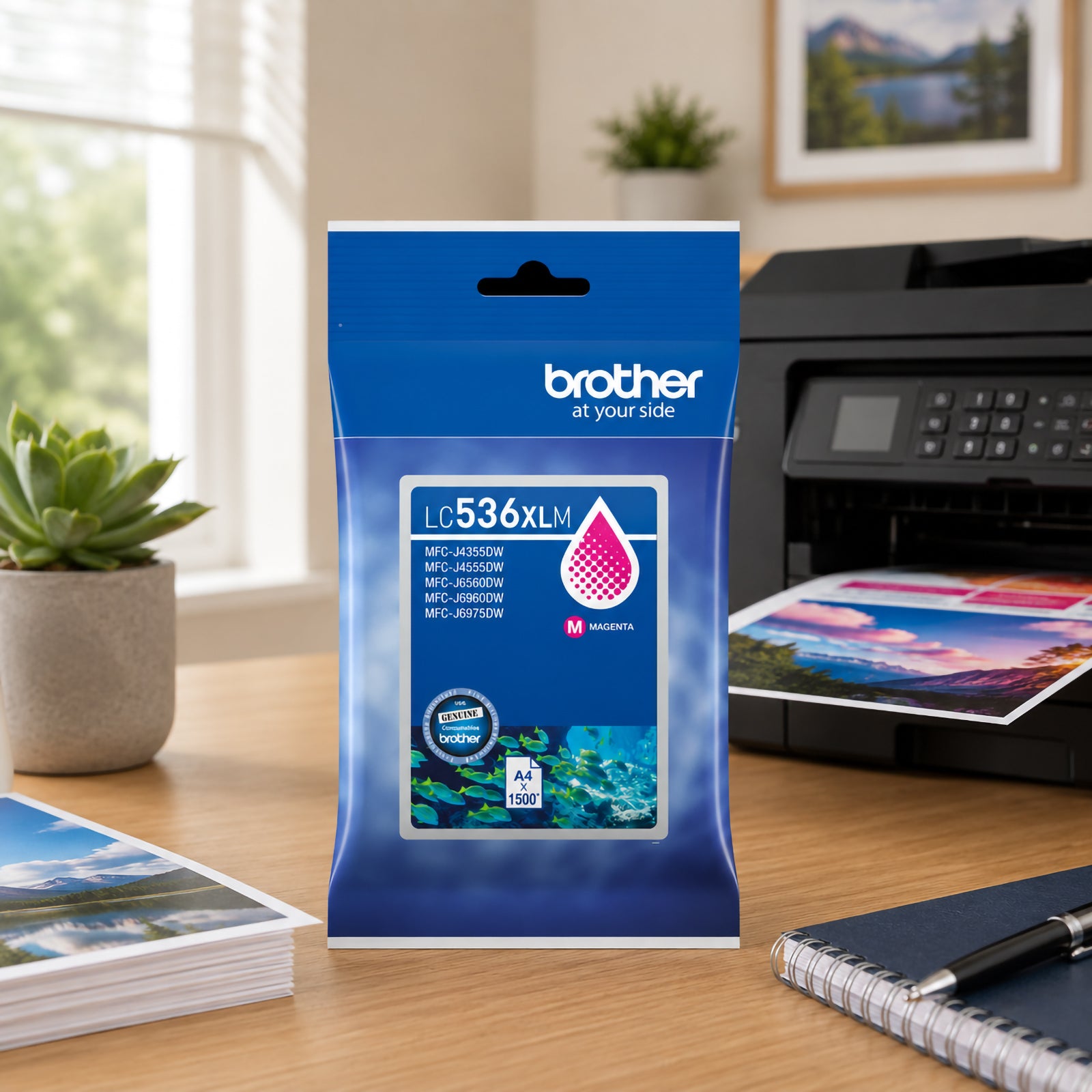 Lifestyle product image featuring the Brother LC536XLM High Yield Magenta Ink Cartridge standing on a desk beside a Brother printer producing vivid landscape photographs. Printed images, stationery and a potted succulent plant surround the cartridge packaging, reinforcing its use for high quality photo printing, colourful presentations and everyday office productivity.