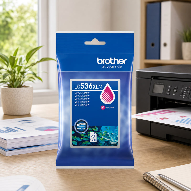 Brother LC536XLM High Yield Magenta Ink Cartridge displayed on a professional office desk beside a Brother colour printer actively producing vibrant photo prints. The packaging stands upright in a bright workspace with a notebook, pen and decorative plant visible in the background. The image highlights the cartridge's suitability for colour rich printing projects, creative work and professional document production.