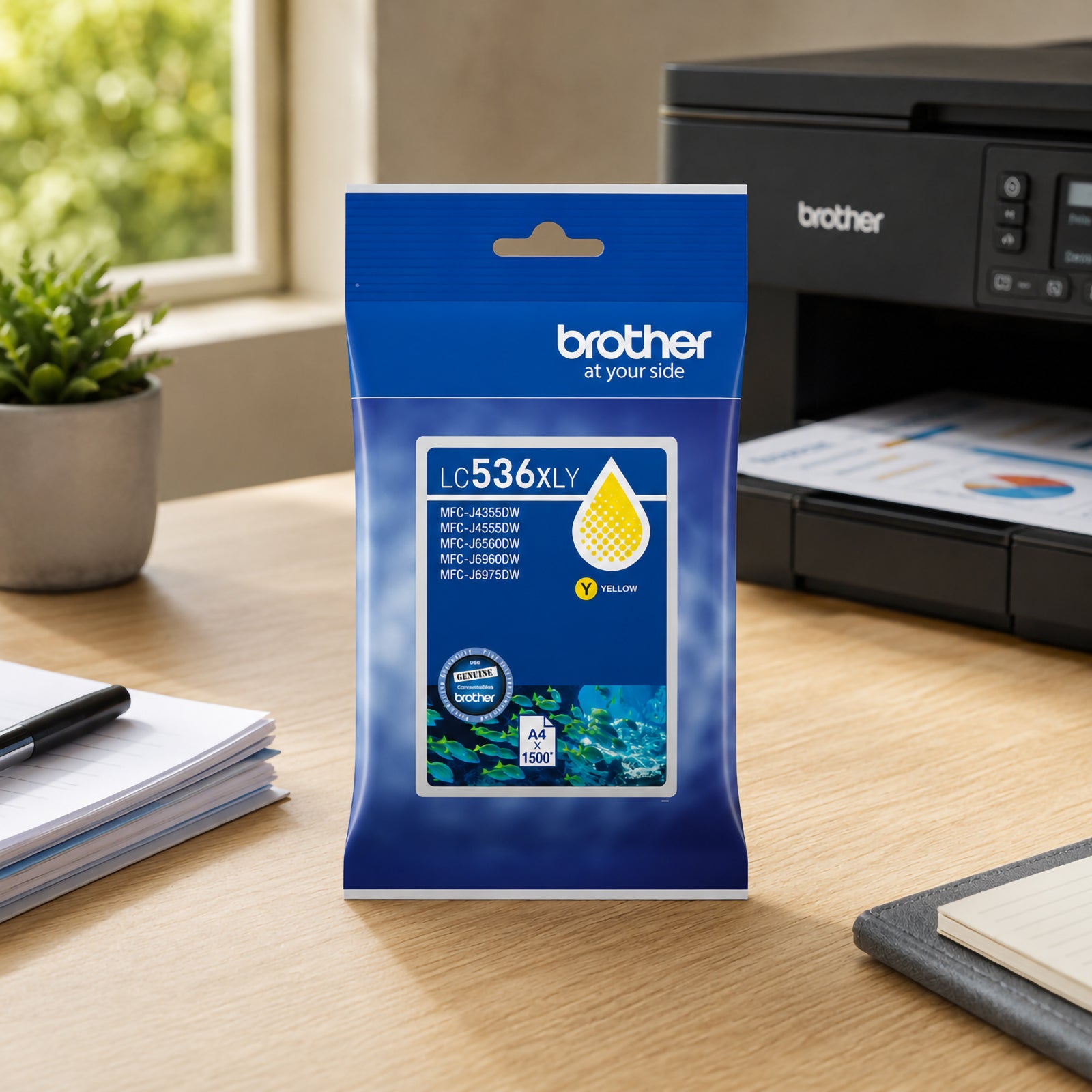 Brother LC536XLY genuine yellow ink cartridge presented in a modern office setting with a Brother printer, notebook, coffee cup and indoor plant. The packaging is the central focus, displaying compatibility information and high yield performance of up to 1,500 pages. The image conveys reliable colour printing for presentations, charts, educational resources and business communications.