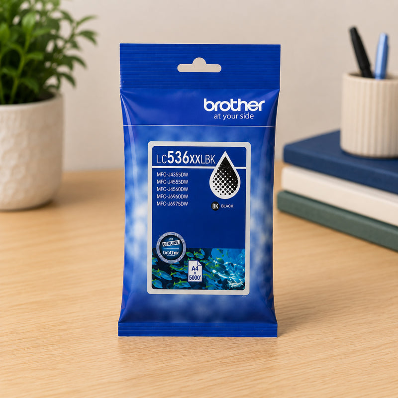 Front facing view of the Brother LC536XXLBK super high yield black ink cartridge packaging displayed on a tidy office desk with books, stationery and decorative greenery. The image emphasises genuine Brother consumables designed for consistent document printing.