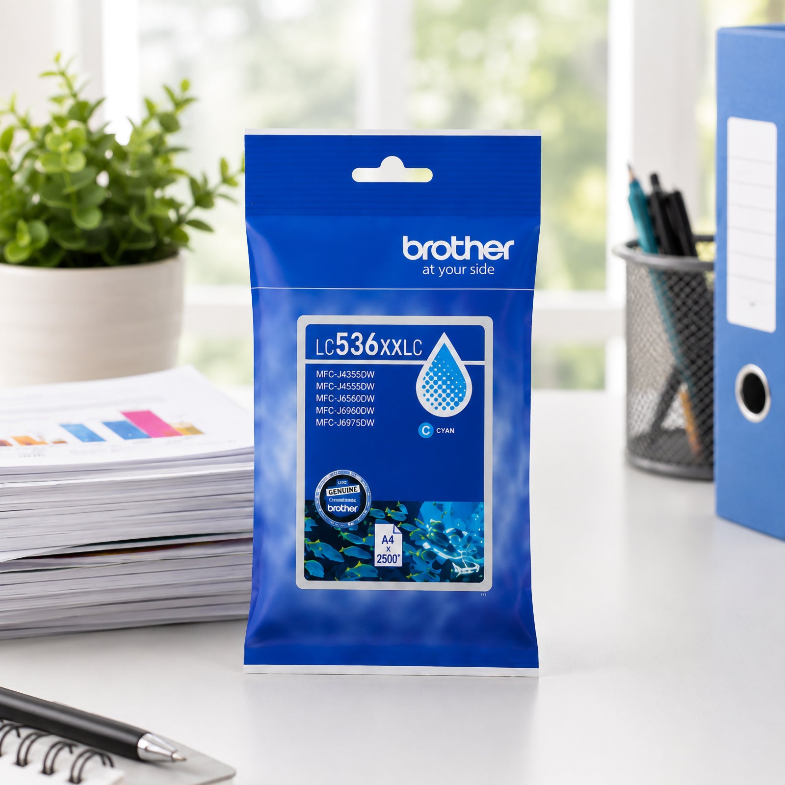 Front facing display of the Brother LC536XXLC super high yield cyan ink cartridge package on a modern office desk with printed reports, stationery and filing materials in the background. The image emphasises genuine Brother consumables designed for professional printing applications.