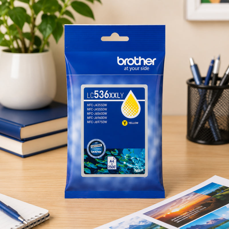 Front facing display of the Brother LC536XXLY super high yield yellow ink cartridge package positioned on a tidy office desk with stationery, printed documents and indoor plants. The image emphasises professional printing quality and high yield performance for business users.