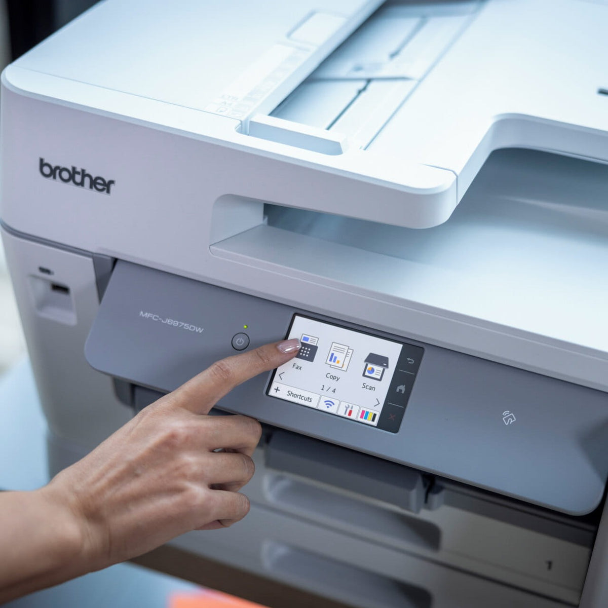 Finger tapping the Fax icon on the 8.8cm colour touchscreen of the Brother MFC-J6975DW, with Copy and Scan icons, a Shortcuts tab and the NFC symbol on the panel.