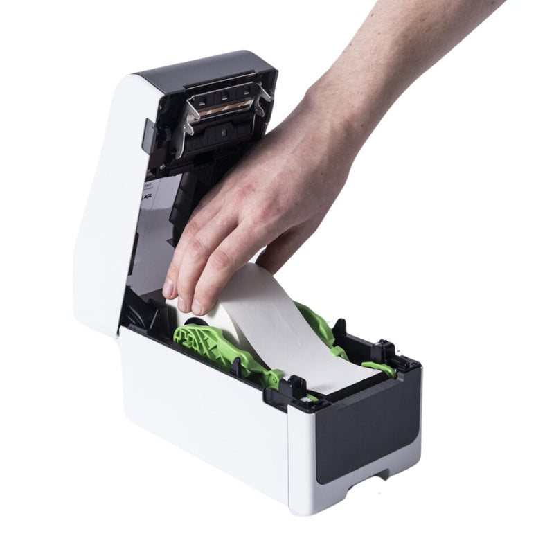 Hand feeding a plain white continuous roll into the open Brother TD-2350D, with the lid raised and the green roll guides holding the roll.