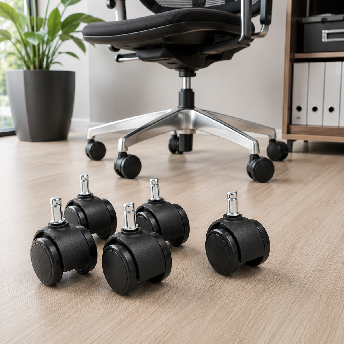 Set of five black Buro 60mm replacement castors positioned in front of an office chair with an aluminium five star base, clearly showing the twin wheel construction and silver mounting stems.