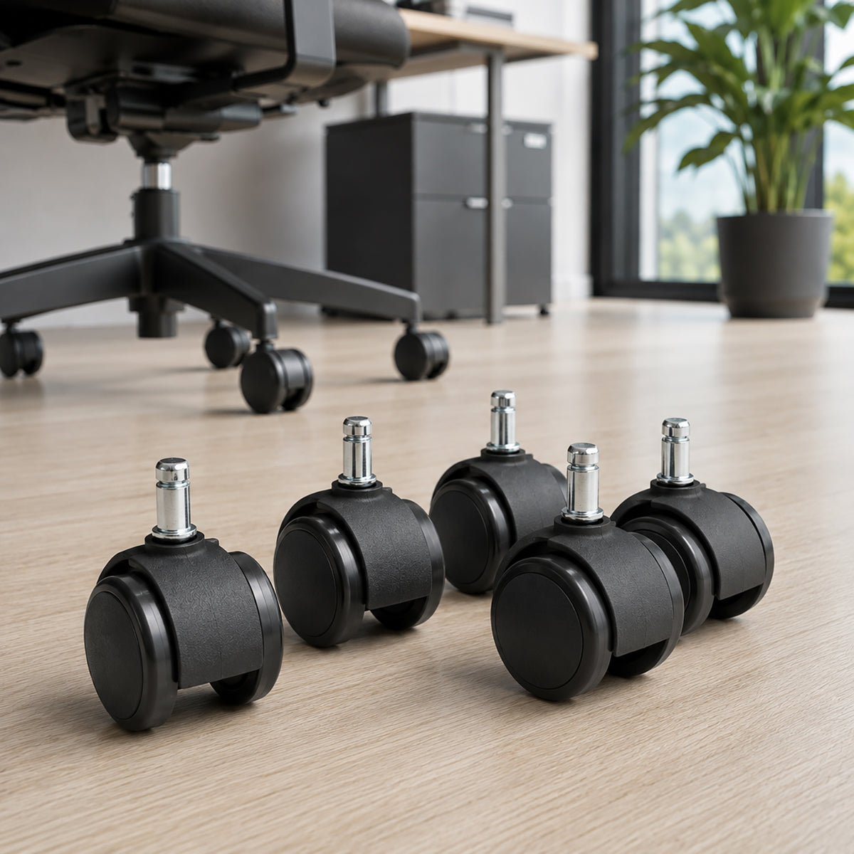Close lifestyle view of five Buro twin wheel chair castors on a light timber floor, highlighting their black commercial construction, 60mm wheels and individual metal stems beside an office chair.