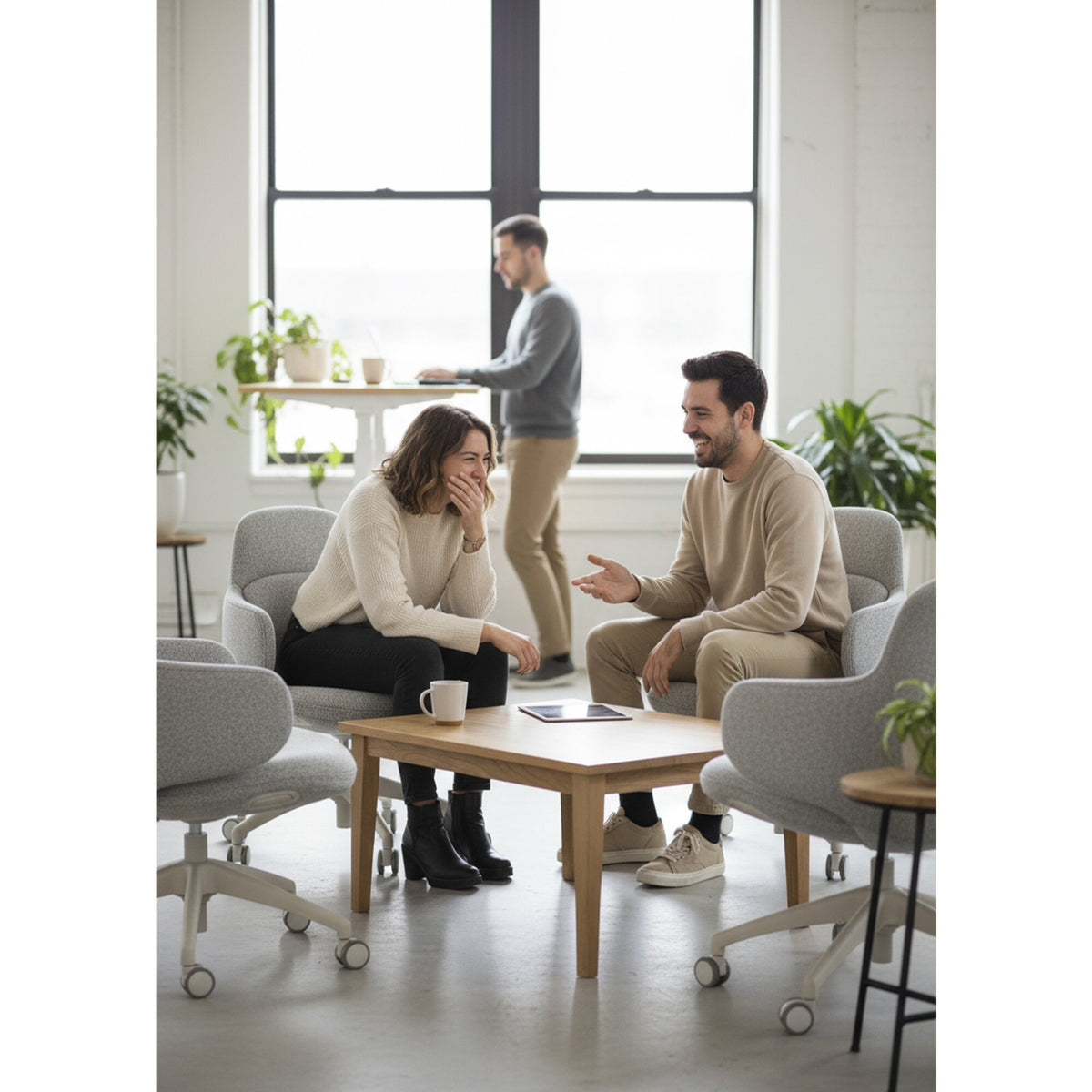 Two people talking at a coffee table in an office lounge, seated in light grey Buro Odyssey chairs