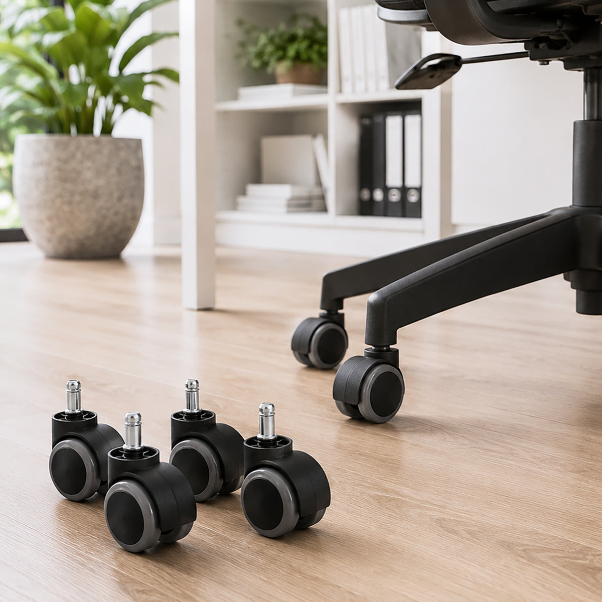Four Buro soft PU replacement castors positioned beside a black office chair on light timber flooring, demonstrating their intended hard floor application and distinctive grey rolling surfaces with black housings.