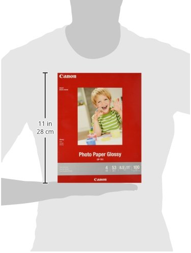 A Canon photo paper pack shown against a light gray silhouette of a person, with a vertical measurement marker indicating 11 in (28 cm) height. The pack is red with a sample photo of a child on the front and Canon branding visible.