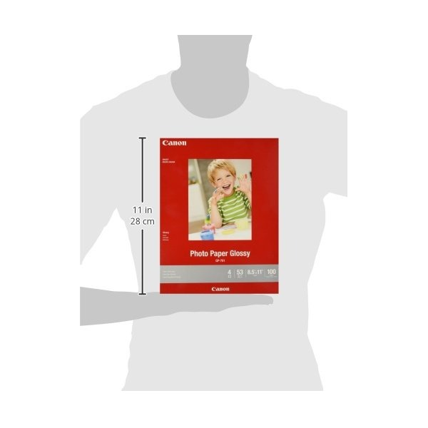 A Canon photo paper pack shown against a light gray silhouette of a person, with a vertical measurement marker indicating 11 in (28 cm) height. The pack is red with a sample photo of a child on the front and Canon branding visible.
