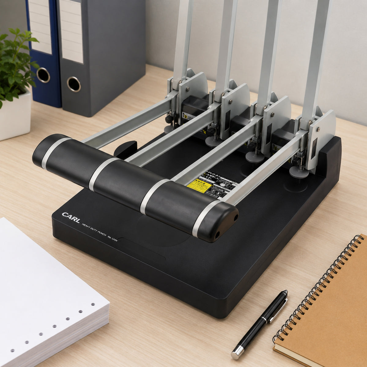 Store image: office desk scene with a Carl No.124N punch beside folders, a notebook and loose paper