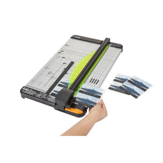Hand drawing the cutting head down the DC630 rail to trim photo prints, with cut photo strips lying beside the base