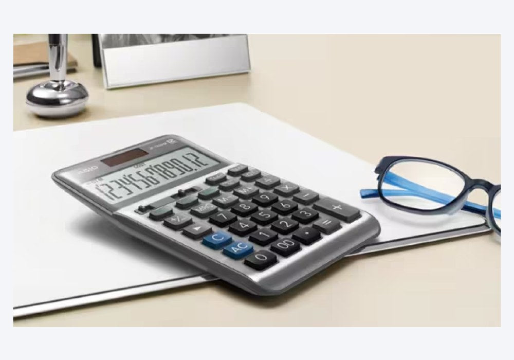 DF120FM calculator lying on paperwork on a desk beside a pair of glasses