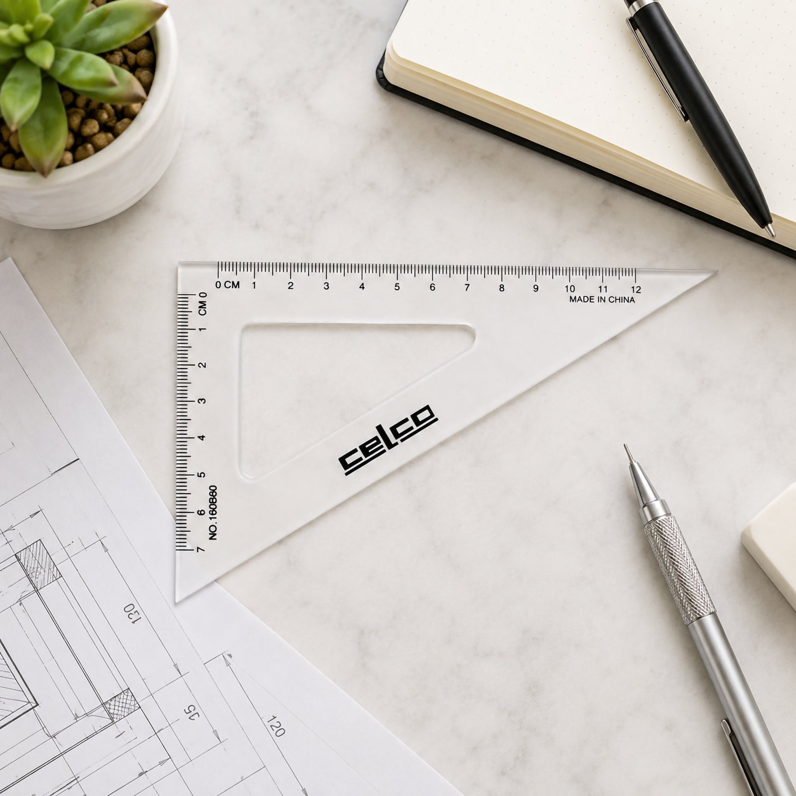 Top view of the Celco 16cm clear 60 degree set square displayed on a clean desktop beside engineering drawings, a notebook, drafting pencil and eraser. The transparent design and metric graduations are clearly visible in an organised workspace.