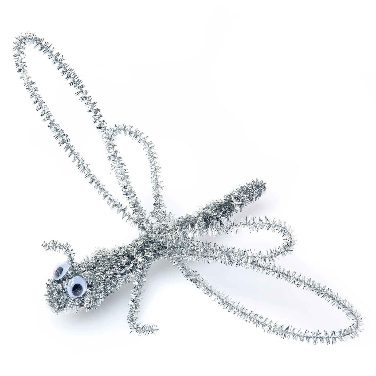 Silver tinsel chenille stem shaped into a dragonfly with googly eyes against a plain background. The detailed design demonstrates the flexibility and sculpting potential of the metallic stems for creating insects, animals and imaginative three dimensional models.