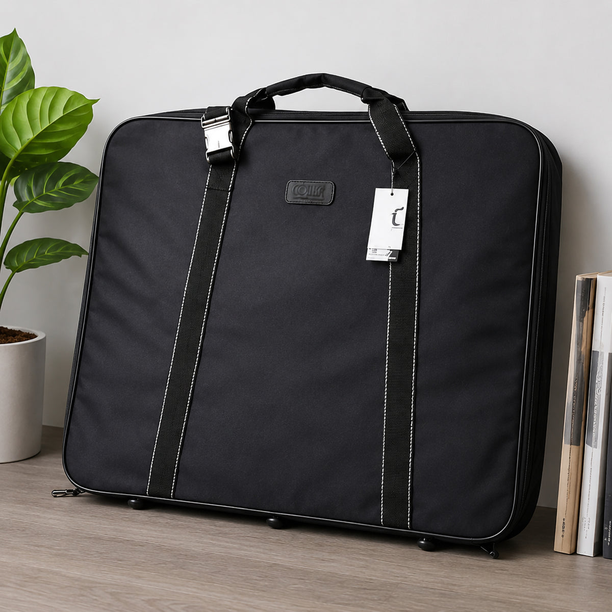 Colby Art A2 black soft sided art bag standing upright in a professional creative workspace. The front view clearly shows the structured body, sewn carry handles, reinforced straps, zippered perimeter and protective feet, presenting a smart storage solution for artwork, design projects, documents and other A2 creative materials.