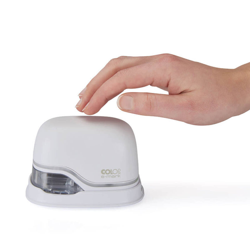 Hand resting on top of the white Colop e-mark handheld printer on a plain white background, showing its compact size