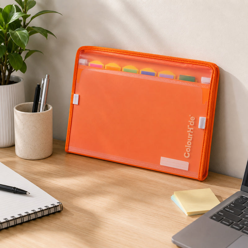 Styling image, possibly computer generated: tangerine expanding file standing on a desk beside a pen pot, notebook and laptop