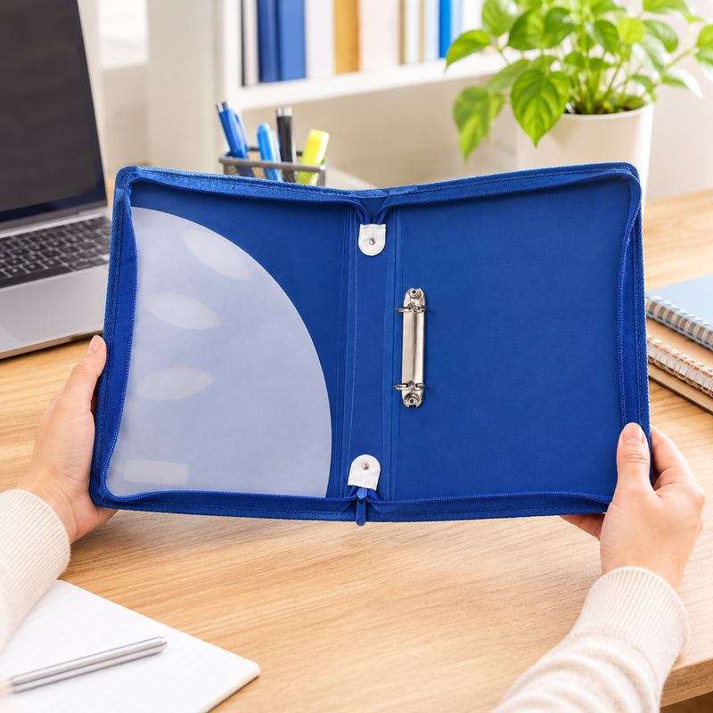 Illustrative scene from our earlier listing: hands holding an unzipped blue binder open at a desk with a laptop behind
