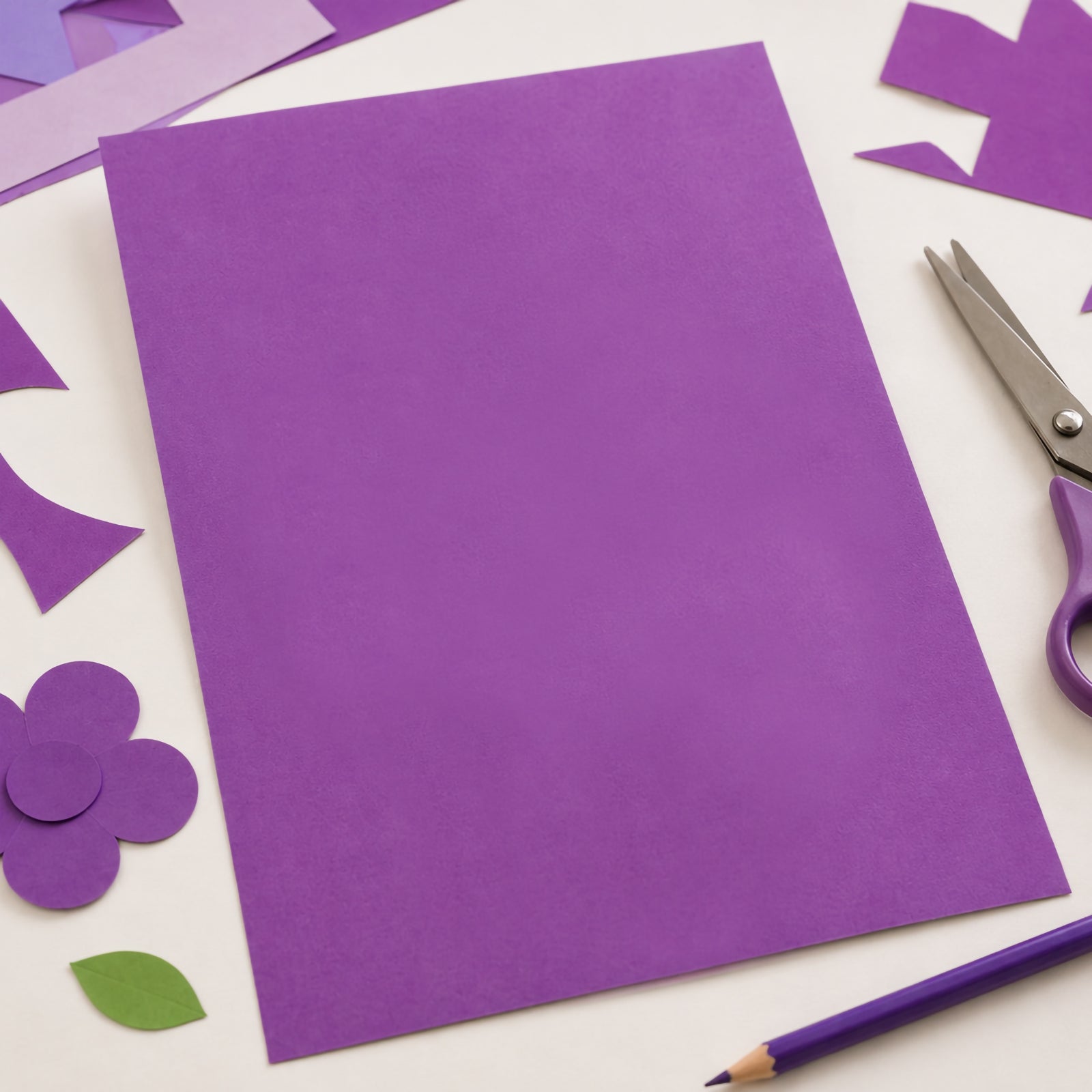 Single sheet of lilac coloured board placed on a craft table surrounded by cut paper shapes, scissors and drawing tools. The image demonstrates the board's versatility for cutting, decorating, floral themed crafts, classroom activities and creative paper projects.