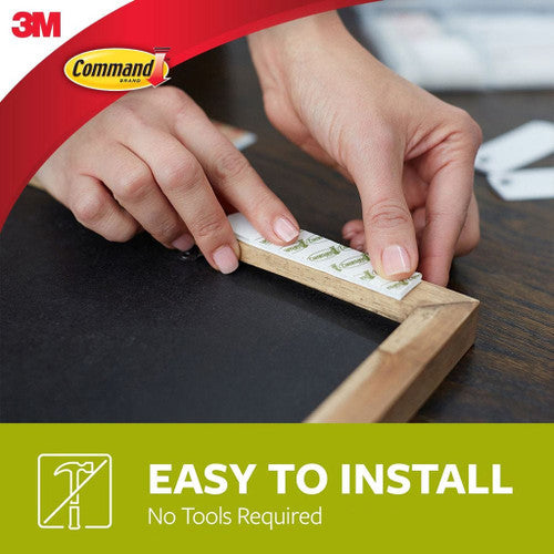 Hands cleanly removing Command strips from a wall without damage