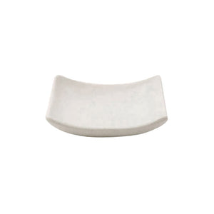 Compass curved white melamine soap dish with a fine stoney grain texture, both raised ends visible from a low three-quarter angle