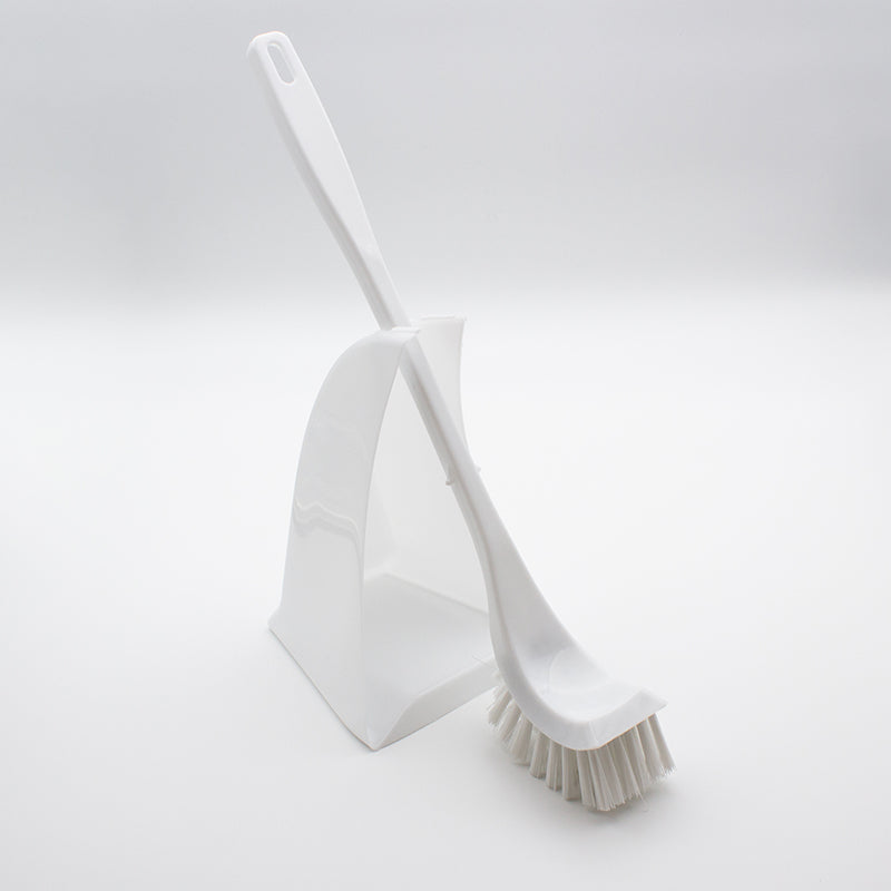 White brush leaning across the open back of its white holder with the curved head resting on the floor