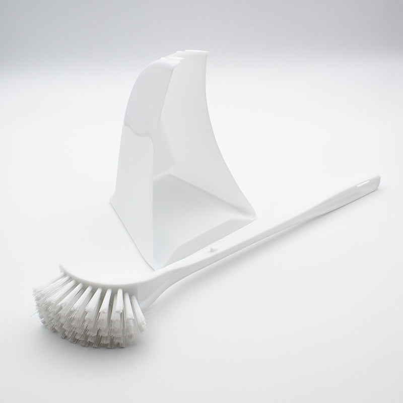 White brush lying beside the empty white holder, showing the curved bristle head and long handle with a hanging hole