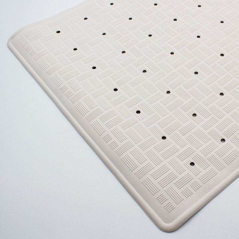 Angled view of the small bath mat top surface, a basket-weave pattern broken by evenly spaced round drain holes