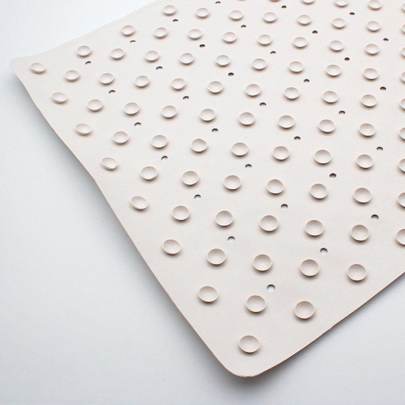 Underside of the small Compass bath mat covered in small round rubber cups with drain holes between the rows