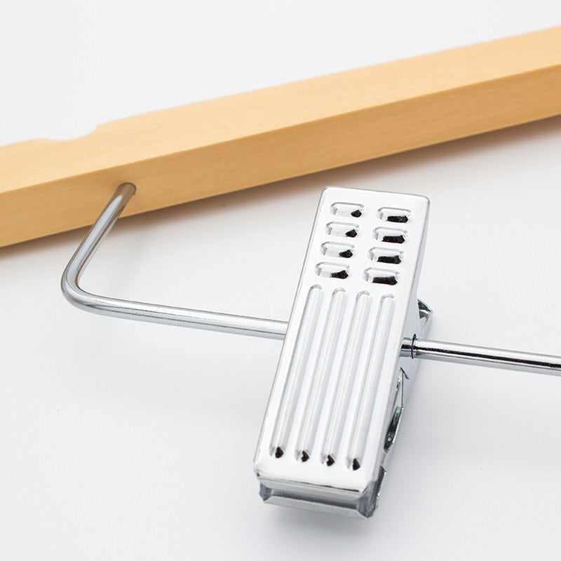 Chrome clip with a slotted face hanging from the wire bar where it enters the light wood shoulder of the hanger
