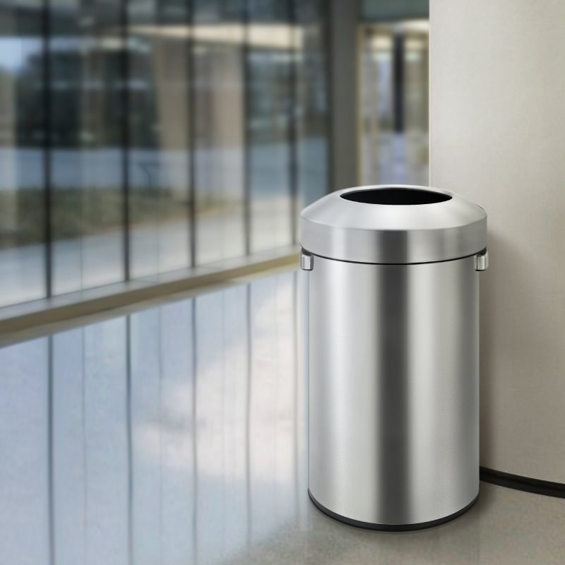 Compass Urban stainless bin standing beside a glass wall in a bright office foyer with a grey floor