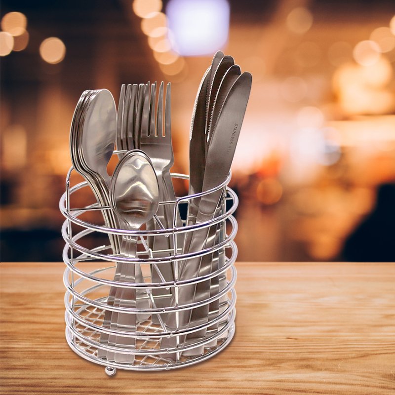 The cutlery set in its wire caddy on a wooden table with a warm, blurred cafe background
