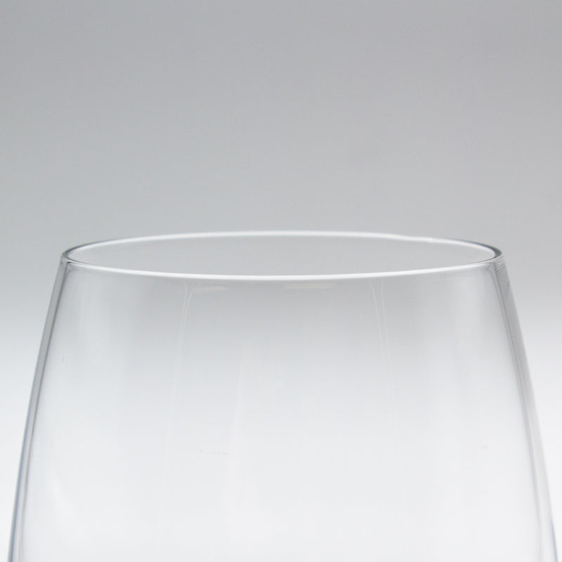 Close-up of the rim of the stemless glass seen side on against a grey background