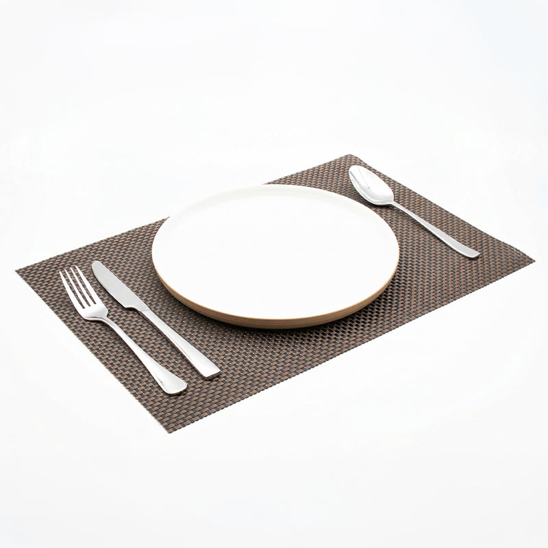 Brown and black placemat photographed at an angle on a white surface, showing its flat rectangular shape