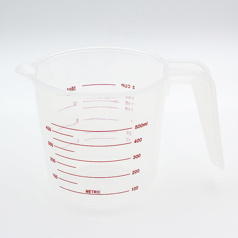 Clear measuring jug on a grey background with the red 100 to 500 ml metric scale facing the camera