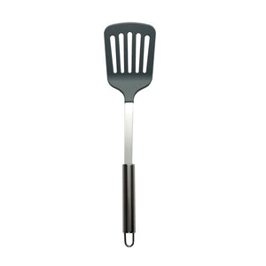 Connoisseur slotted turner on white with a dark grey slotted head, polished stainless steel shaft and black handle insert with a wire loop