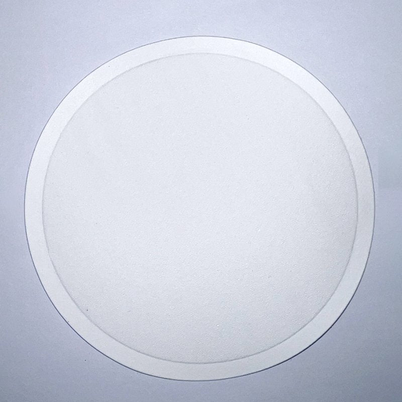Plain white round Connoisseur paper coaster on a pale blue background, with an embossed ring just inside the outer edge