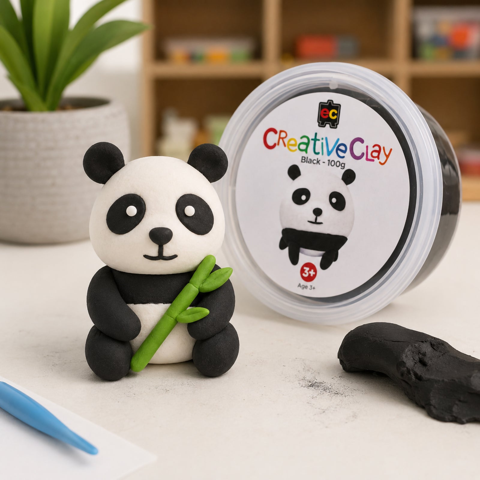 Educational Colours CreativeClay Black 100g container displayed beside a completed panda model and a piece of unused clay. Product packaging is clearly visible, showing the clay's colour, size and suitability for creative classroom and home craft activities.