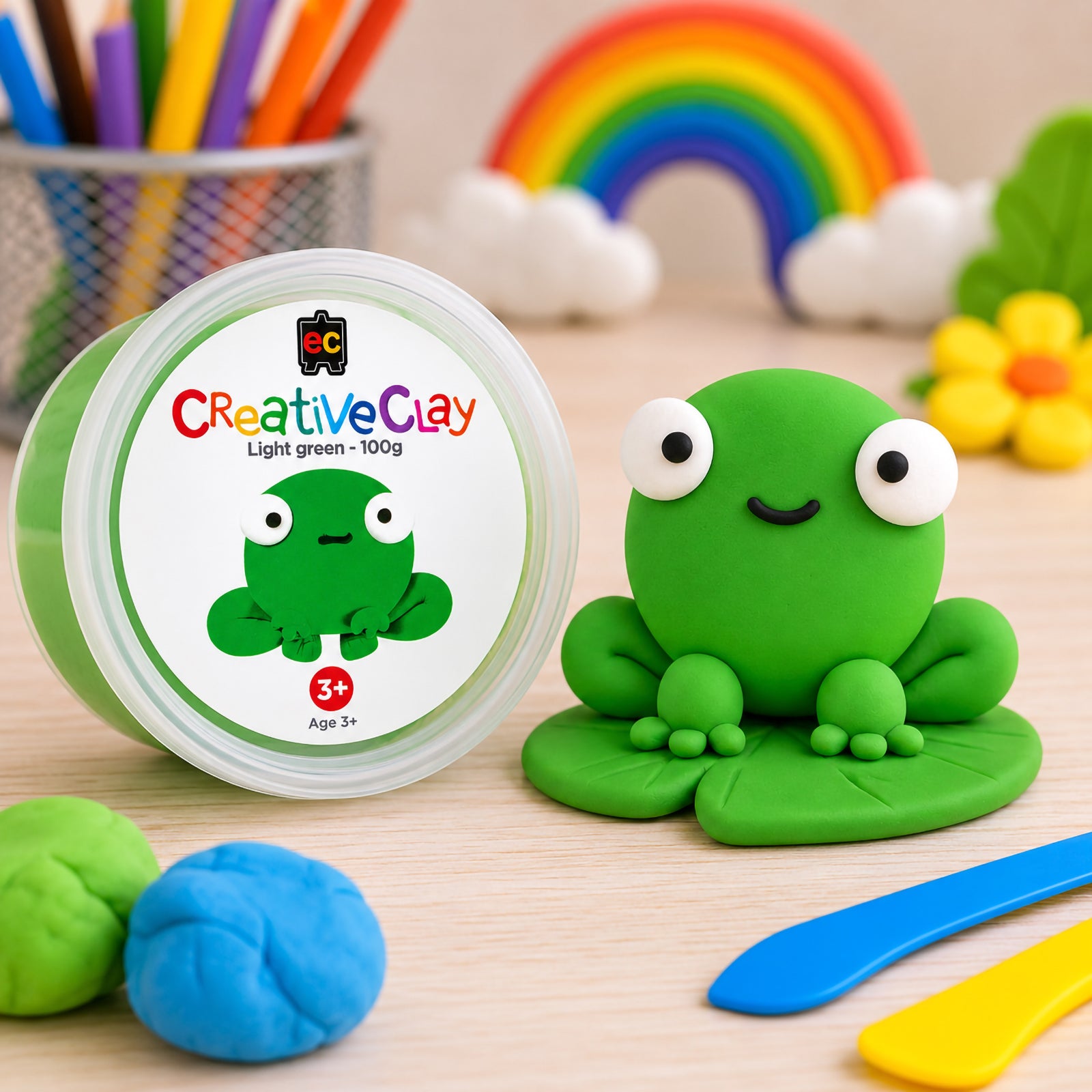 Educational Colours CreativeClay Light Green 100g container displayed beside a completed frog model on a lily pad. The image showcases finished project possibilities and highlights the clay's lightweight air drying properties.