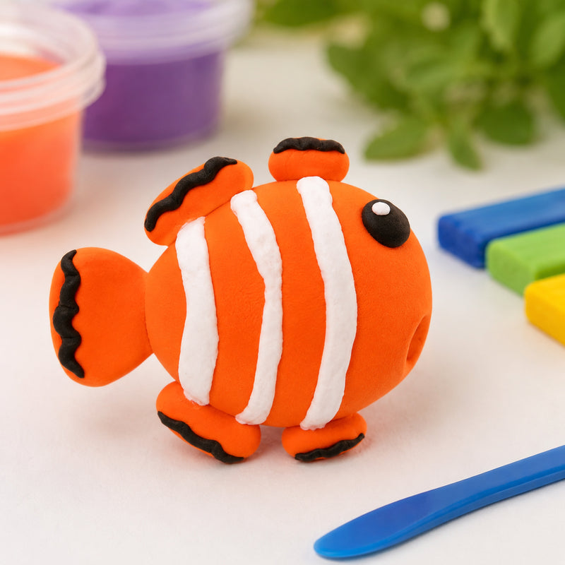 Detailed clownfish sculpture created from orange CreativeClay with white stripes and black accents. The finished model demonstrates the clay's ability to hold fine details and create imaginative underwater themed projects.