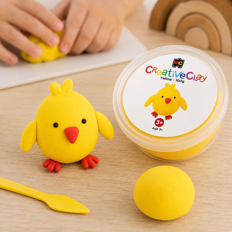Educational Colours CreativeClay Yellow 100g container displayed beside a completed chick model, sculpting tool and clay sample. The image showcases the packaging and illustrates how the clay can be transformed into colourful handcrafted creations.