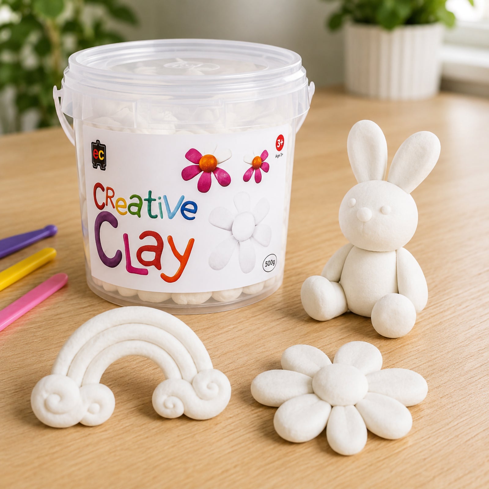 Educational Colours CreativeClay White 500g container displayed with completed white rabbit and flower sculptures. The image highlights the smooth texture of the clay, its ability to hold detailed shapes and its suitability for larger modelling projects and classroom use.